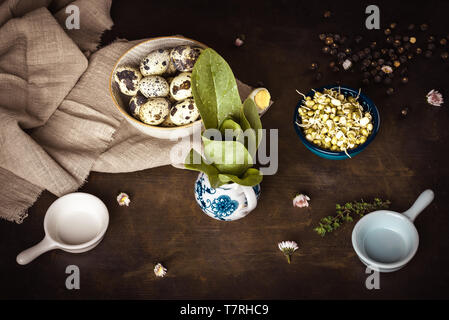 Horizontal photo of vintage wooden board with several bowls which contain mung bean sprouts, quail eggs and spinach. Light cloth is under one bowl. Stock Photo