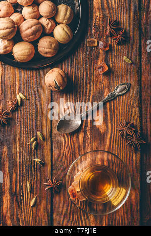 Spiced tea with star anise, cardamom and dried lime in arabic glass over wooden surface. View from above Stock Photo