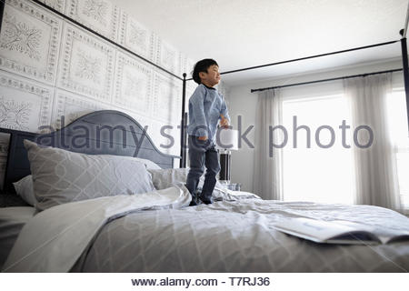 Playful boy jumping on bed