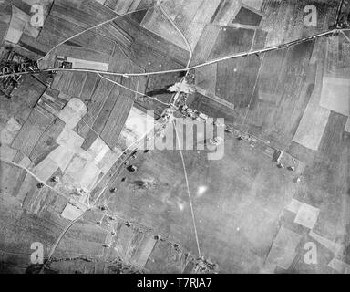 A contemporary British black and white photograph taken in 1917 from an aeroplane during the First World War. Photograph shows the bombing of a target in Northern France. A British aeroplane can be seen in small detail flying just over the road that runs left to right, having just dropped its bombs.  Aerial bombing World war One. Stock Photo