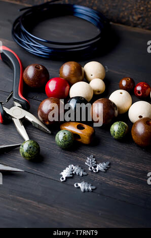 Tools for handmade jewelry. wooden Beads, plier and accessories to create hand made fashion jewelry on dark wooden table Top view Stock Photo