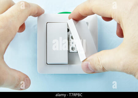 Electrician is installing new european standard light switch making new buttons, electrical maintenance. Stock Photo