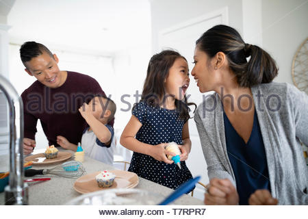 Playful family eating cupcakes in kitchen