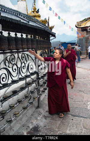 Buddhist monk spinning prayer wheels at a temple at Swayambhunath Stupa also called Monkey Temple in Kathmandu Nepal Stock Photo