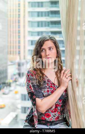 Office buildings glass window of young woman girl sitting face portrait looking sad scared by corporate view dreaming in midtown in NYC Stock Photo