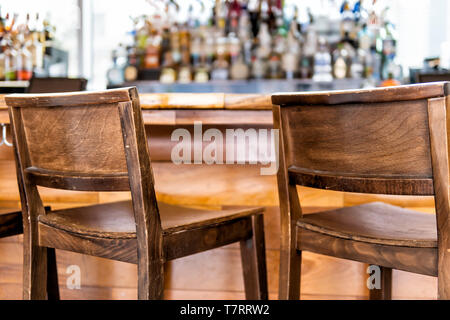 Empty wooden vintage bar stools counter row in drink establishment pub during day closeup of retro wood and nobody Stock Photo