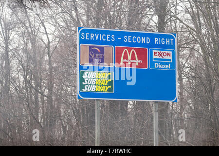 Leesburg, USA - April 6, 2018: Rural Virginia countryside in spring with blue exit sign on highway for food and service such as mcdonalds fast food, s Stock Photo