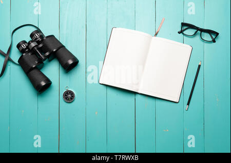 Plan for traveling, binoculars on green wooden floor with notebook and map, journey, find and search concept. Stock Photo