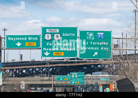 Jersey City, USA - April 8, 2018: Green road sign to interstate highway i-95, Port Newark, airport, Raymond boulevard direction for truck only with ov Stock Photo