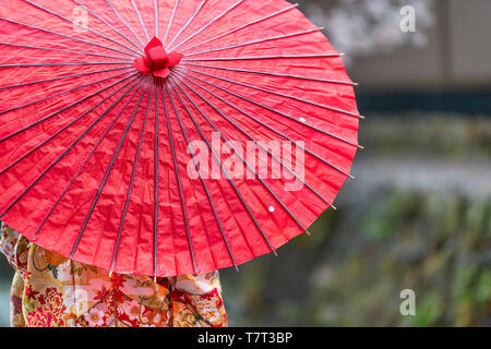 Kyoto, Japan spring with garden park by river and woman in red kimono and umbrella closeup of parasol Stock Photo