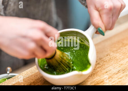 Woman holding Japanese tea cup teapot pot on table closeup holding whisk for matcha stirring hot drink koicha Stock Photo