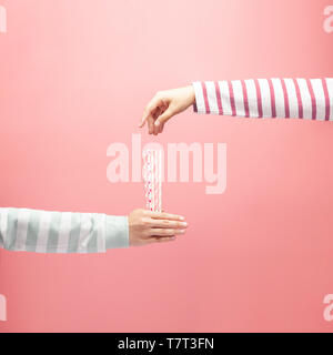 Woman holding straws for someone to draw straws, drawing straws on pink background, draw lots or lucky draw, choosing concept. Stock Photo