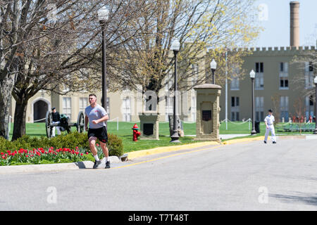 Lexington, USA - April 18, 2018: Man training, jogging or running at Virginia Military Institute main campus grounds with cadets walking in white unif Stock Photo