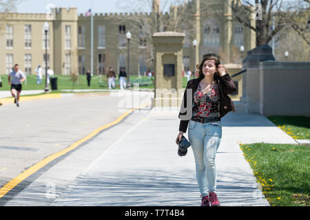 Lexington, USA - April 18, 2018: Young woman, female professional photographer with DSLR camera walking on sidewalk on campus grounds of Virginia Mili Stock Photo