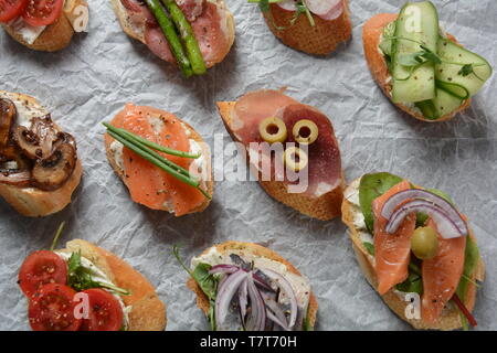 Brushetta or traditional Spanish tapas. Appetizers with Italian antipasti snacks. Variety of small sandwiches with prosciutto, cherry tomatoes, salmon Stock Photo