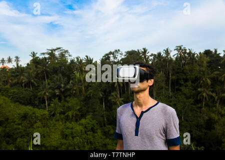 Young man wearing VR glasses in the tropicalforest Stock Photo