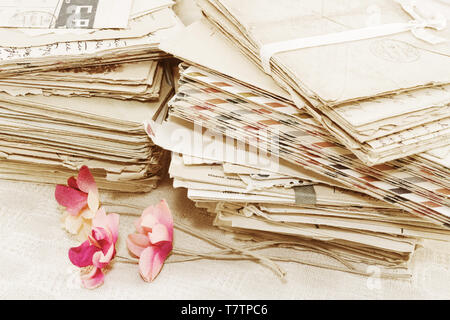 Pile of the old paper postal correspondence and the vintage red artifical flowers Stock Photo