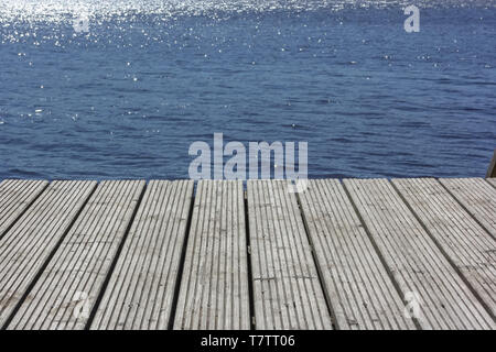 Idyllic view of the wooden pier in the lake or river mooring surface reflecting mirror sky Stock Photo