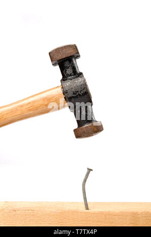 Old hammer hitting a nail. Isolated on white. Stock Photo