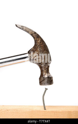 Old hammer hitting a nail. Isolated on white. Stock Photo