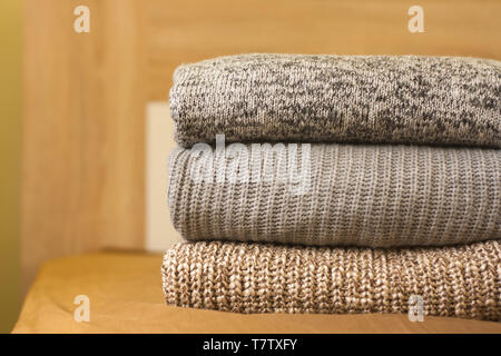 A pile of knitted sweaters on the wood bed. Warm comfortable clothes. Stock Photo