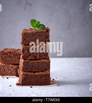 pile of square slices of baked brownie pie on a white surface, close up Stock Photo