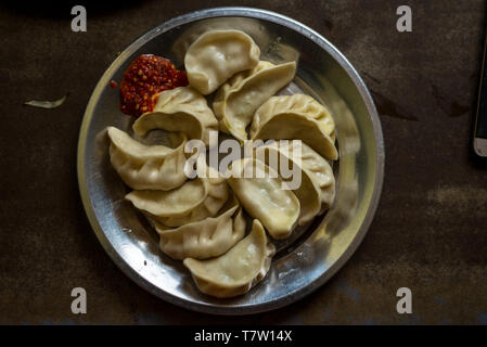 Photo of Nepalese traditional dumpling momos steamed served with tomato chutney, schezwan sauce in himalayas Stock Photo