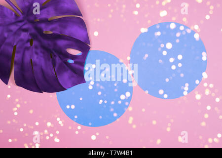 Vibrant bold purple tropical monstera leaf on pink background with copy space and with bokeh lights. Art neon surrealism concept Stock Photo