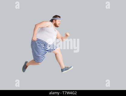 Funny man in striped shorts runs on a gray background. Stock Photo