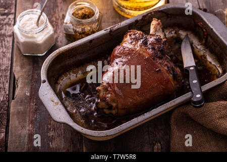Baked Pork knuckle with beer and cauliflower in roast pan. Stock Photo