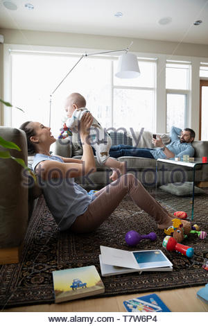 Happy mother playing with baby son in living room