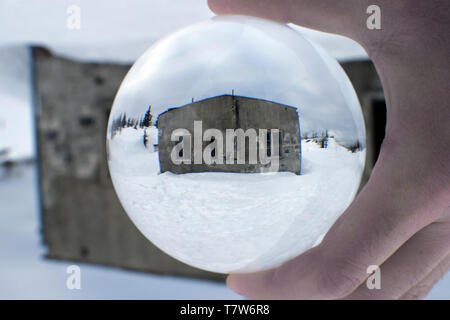 Old abandoned mountains building in crystal ball. Winter mountain landscape. Stock Photo