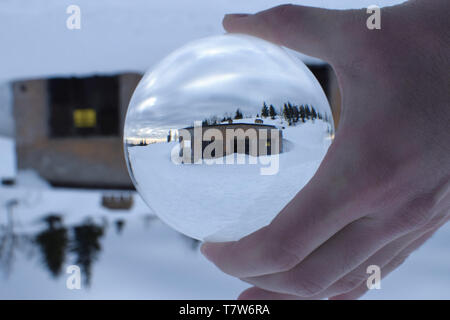 Old abandoned mountains building in crystal ball. Winter mountain landscape. Stock Photo