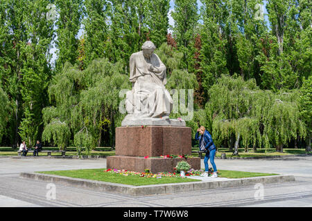 A woman lays flowers at the weeping Motherland statue at the Soviet War Memorial (Sowjetisches Ehrenmal) in Berlin Treptow, Germany Stock Photo