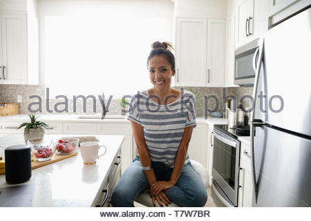 Portrait confident woman drinking coffee in morning kitchen