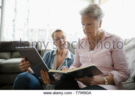 Daughter and senior mother paying bills, using digital tablet