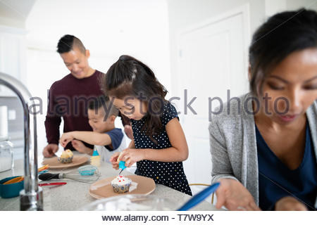 Family decorating cupcakes in kitchen