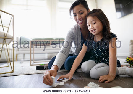 Mother and daughter playing with dominos on floor