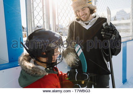 Brother and sister playing outdoor ice hockey