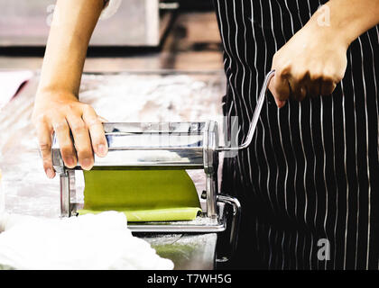 Chef making dough for pastry, fresh pasta and pasta machine on kitchen Stock Photo