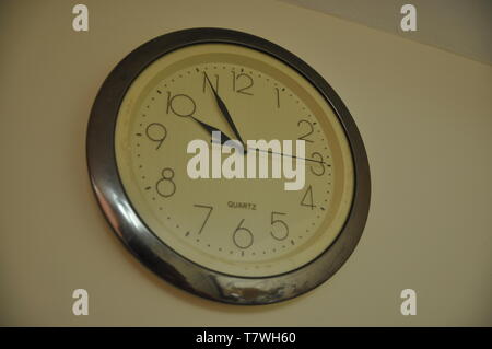 A round clock hangs on the wall Stock Photo