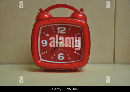 A square and red clock on the table Stock Photo