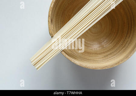 High angle view of uncooked rice noodles and wooden plate on white background. Stock Photo