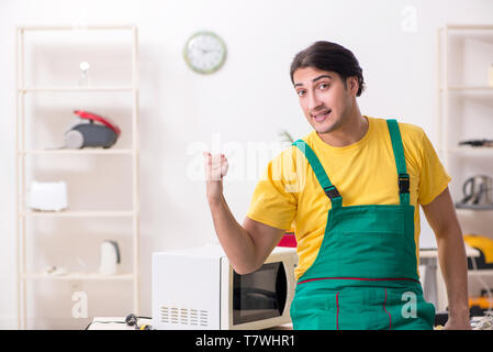 Young repairman repairing microwave in service centre Stock Photo