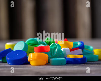 Image of colorful plastic caps on a wooden table with blurry background Stock Photo