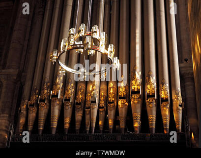 detail of ornately decorated Organ pipes with circular pendant chandelier light fitting in the Cathedral, Carlisle, Cumbria, England