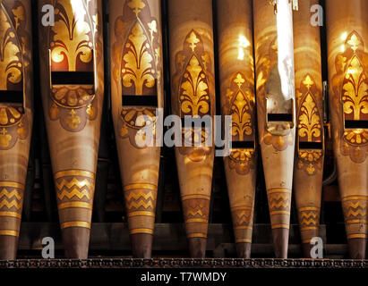 detail of ornately decorated Organ pipes with fleur-de-lys design in golden sunlight in Carlisle Cathedral, Cumbria, England