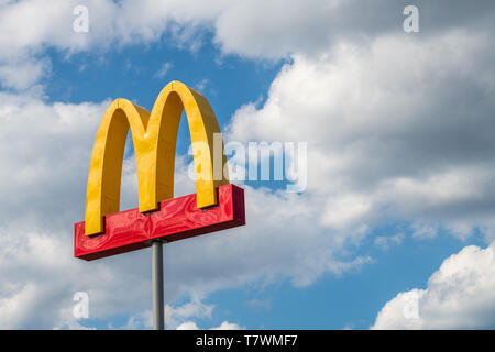 McDonalds sign isolated against cloudy blue sky Stock Photo