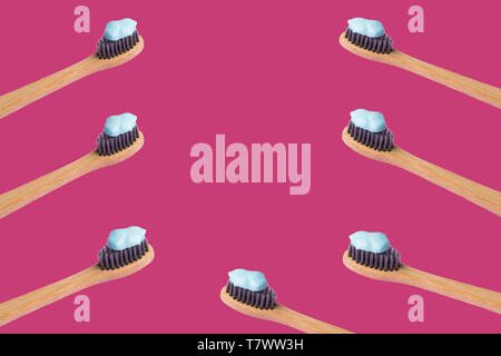 Frame of bamboo toothbrushes with blue toothpaste isolated on pink background. Personal dental hygiene concept. Zero waste Stock Photo