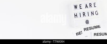 Creative top view flat lay of desk with we are hiring text on lightbox with copy space on white background in minimal style. Concept of new job, hirin Stock Photo